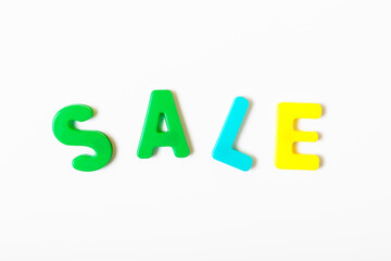 The word SALE made of multicolored letters on a white background. Concept for sales and discounts in stores. Thrifty shopping concept. Top view, flat lay, minimalism.