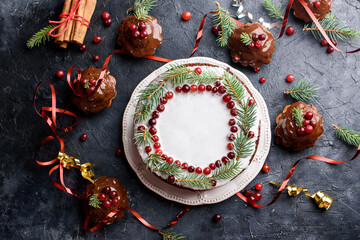 New Year's chocolate cake, with white glaze, decorated with firs and cranberries. Cupcakes with chocolate glaze. Holiday food and content