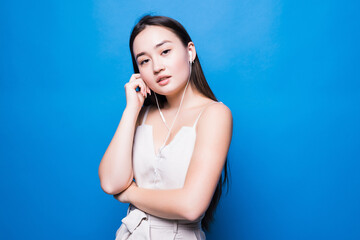 Fototapeta premium Portrait young asian woman listening music on phone with earphone isolated on blue background.