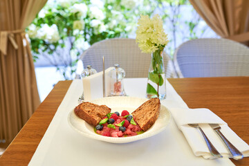 Tuna tartare with raspberries and blueberries in a white plate.