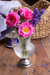 Small vintage glass vase with wild pink roses and purple lavender