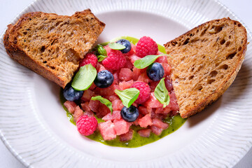 Tuna tartare with raspberries and blueberries in a white plate. - Powered by Adobe
