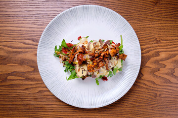 Bruschetta with roast beef and chanterelles on a white plate on a wooden table.