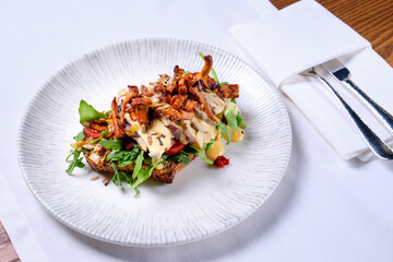 Bruschetta with roast beef and chanterelles on white.