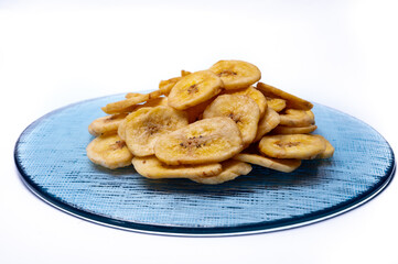 Healthy snack, crispy dehydrated unsugared banana chips on recycled glass plate on white background
