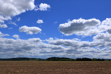 Plowed or Ploughed Field in Countryside and Blue Sky with Clouds over Horizon
