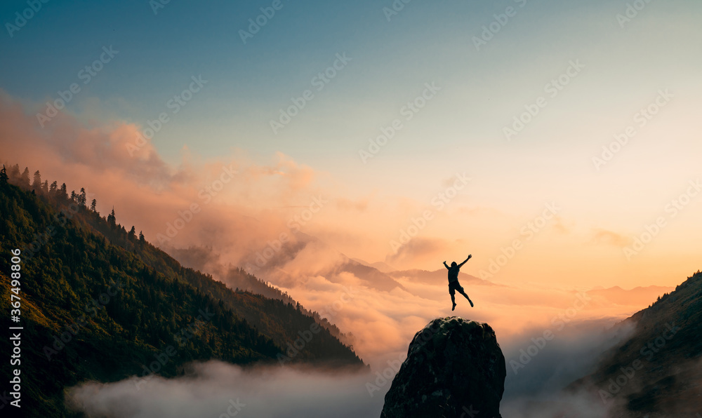 Wall mural silhouette of a man jump and rises arms up on a peak. the happiness and excitement of beeing success - Wall murals