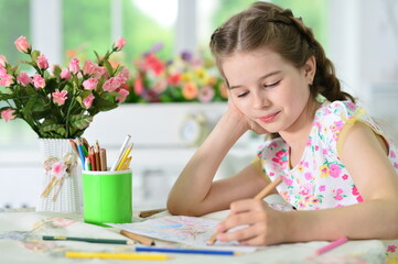 Portrait of cute girl drawing picture at home