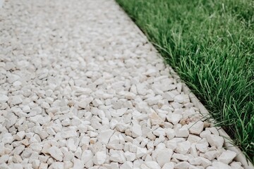 Closeup shot of marble pebbles on the pathway beside a lawn