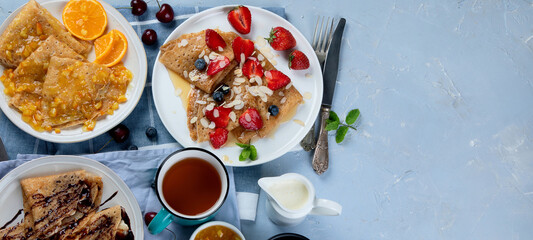 Variety of homemade crepes on grey background.