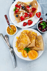 Variety of homemade crepes on grey background.