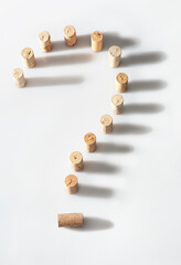 Wine bottle corks arranged to form a question mark on a white background.