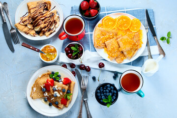 Variety of homemade crepes on grey background.