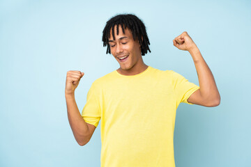 Young african american man isolated on blue background celebrating a victory