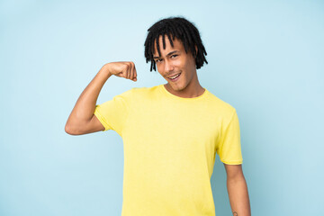 Young african american man isolated on blue background doing strong gesture