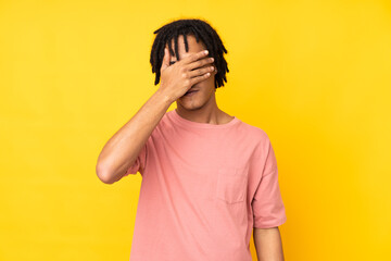 Young african american man isolated on yellow background covering eyes by hands. Do not want to see...