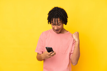 Young african american man isolated on yellow background surprised and sending a message