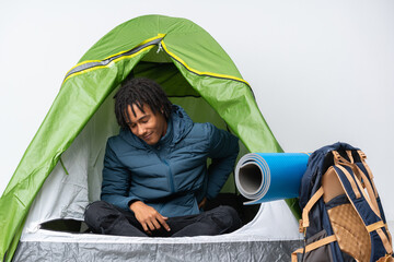Young african american man inside a camping green tent suffering from backache for having made an...