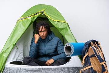 Young african american man inside a camping green tent with angry gesture