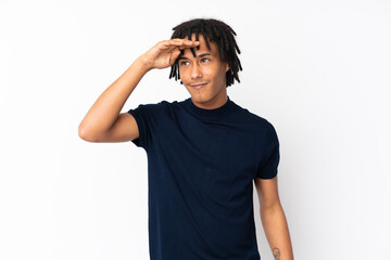 Young african american man isolated on white background looking far away with hand to look something