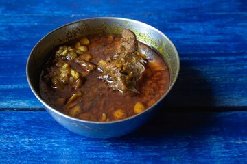 Closeup of Goat Curry in a Steel Bowl Isolated on Blue Colored Wooden Background