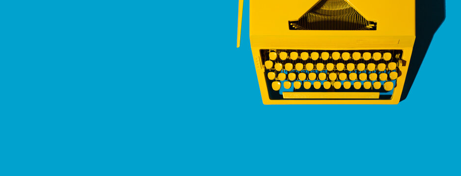 Yellow bright typewriter on blue background. Creativity concept
