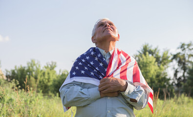 Naklejka na ściany i meble Patriotic senior man celebrates usa independence day on 4th of July with a national flag in his hands. Constitution and Citizenship Day. National Grandparents day