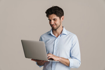 Image of smiling businesslike brunette man working with laptop