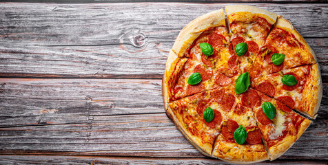 Obraz na płótnie Canvas Pepperoni Pizza with Mozzarella cheese, salami, Tomato sauce, pepper, Spices and Fresh basil. Italian pizza on wooden table background