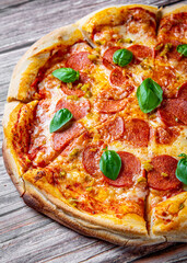 Pepperoni Pizza with Mozzarella cheese, salami, Tomato sauce, pepper, Spices and Fresh basil. Italian pizza on wooden table background