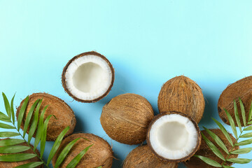 Top view shot of coconuts, whole and cracked on halves on paper textured background with a lot of copy space for text. Background with raw fruit of tropical palm. Flat lay.