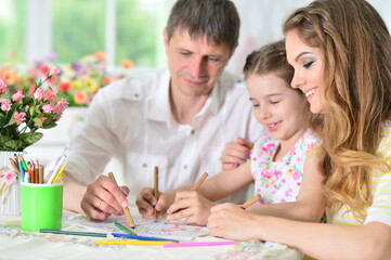 Girl with mother and father drawing at home