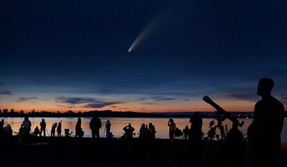 Comet Neowise and people with cameras and telescope silhouetted by the Ottawa river watching and...