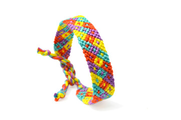 Selective focus of tied woven friendship bracelet with bright colorful pattern handmade of thread isolated on white background
