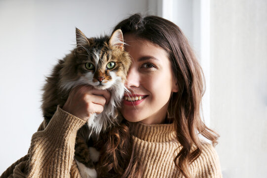 Charismatic young woman playing with her adorable cat.