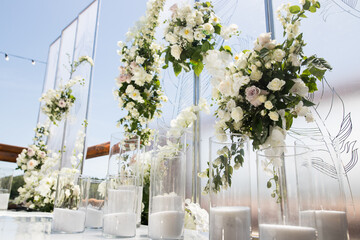 Close up of wedding ceremony with white transparent screens and fresh white flowers and candles