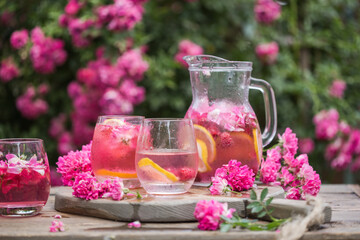 Fresh Rose lemonade or cokctail  with ice and fresh roses over natural garden