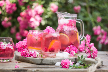 Fresh Rose lemonade or cokctail  with ice and fresh roses over natural garden