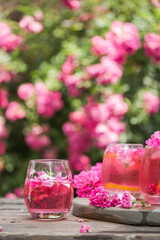 Fresh Rose lemonade or cokctail  with ice and fresh roses over natural garden