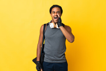 Young sport African American man with braids with bag isolated on yellow background shouting with mouth wide open