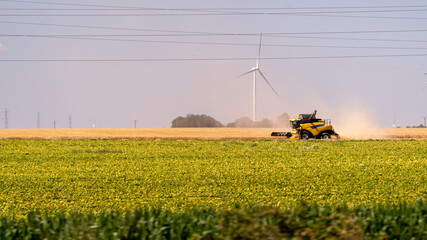 Combine harvester working in a field with wind turbine