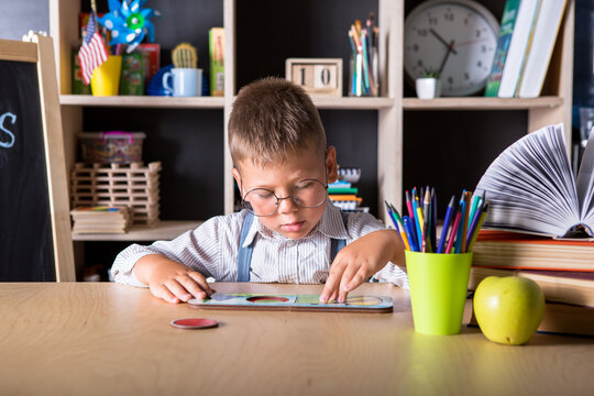 Elementary school. Back to school. Kid is learning in class on background of blackboard. Educational games and toys. Close up.  Back to school. Great study achievement. Funny little boy pointing up on