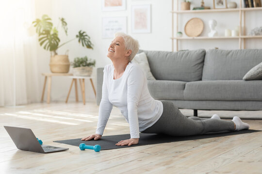 Online Yoga. Senior Woman Standing In Cobra Pose In Front Of Laptop