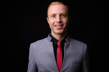 Businessman with blond hair against black background