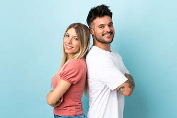 Fototapeta premium Young caucasian couple isolated on blue background keeping arms crossed