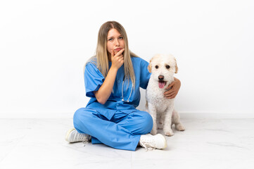 Young veterinarian woman with dog sitting on the floor thinking