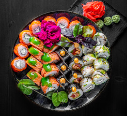 set of sushi roll with salmon, avocado, cream cheese, cucumber, rice, caviar, eel, tuna in plate on black wooden table background