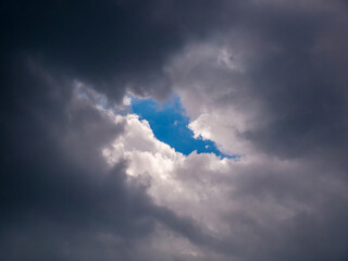 A piece of blue sky in a hole in the thick rain clouds