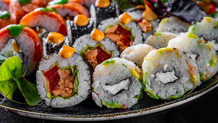 set of sushi roll with salmon, avocado, cream cheese, cucumber, rice, caviar, eel, tuna in plate on black wooden table background