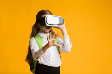 Obraz premium Schoolgirl Wearing VR Glasses Experiencing Virtual Reality In Studio